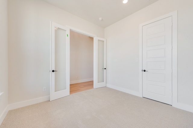 unfurnished bedroom with light colored carpet, french doors, and a closet