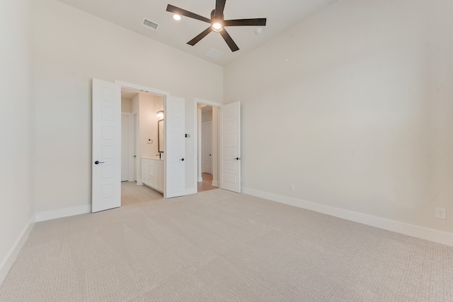 unfurnished bedroom featuring ceiling fan, light colored carpet, ensuite bathroom, and high vaulted ceiling