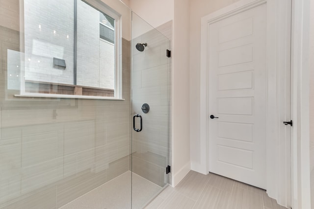 bathroom with tile patterned floors, a shower with shower door, and plenty of natural light