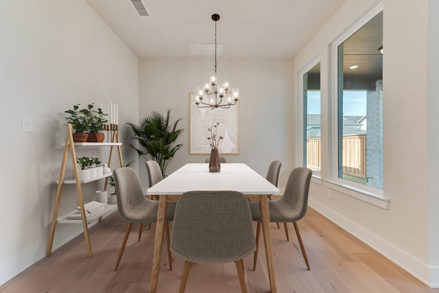 dining room featuring a chandelier, light hardwood / wood-style floors, and a water view