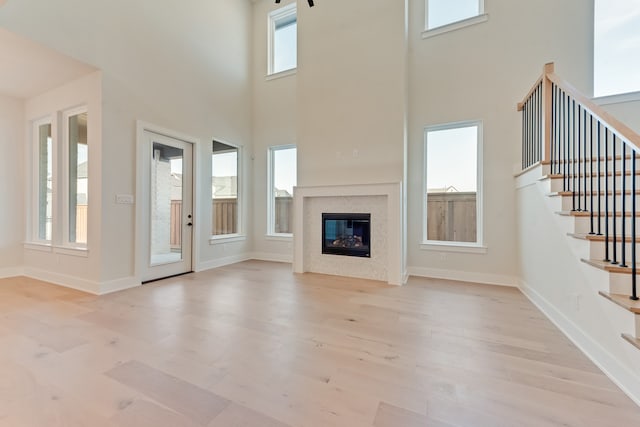 unfurnished living room featuring light hardwood / wood-style floors, a premium fireplace, and a healthy amount of sunlight