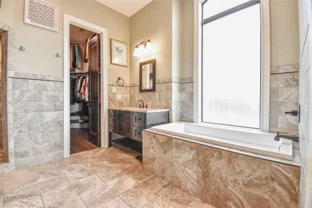 bathroom featuring vanity, tiled tub, and tile walls