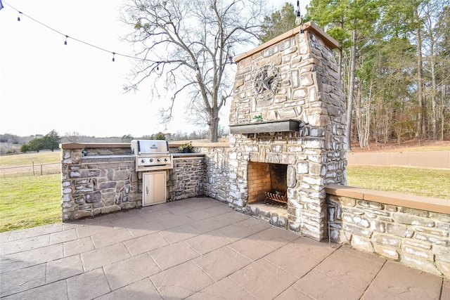 view of patio with area for grilling, an outdoor stone fireplace, and grilling area