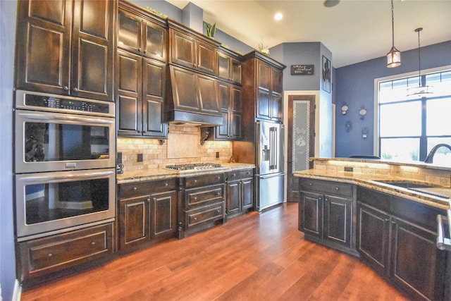 kitchen featuring hanging light fixtures, sink, stainless steel appliances, tasteful backsplash, and dark brown cabinetry