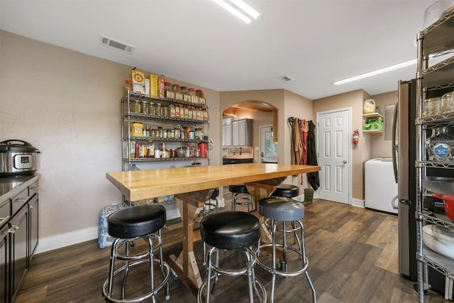 bar featuring dark wood-type flooring, washer / clothes dryer, and butcher block countertops