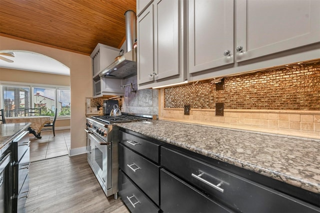 kitchen with wooden ceiling, gray cabinetry, light stone countertops, range with two ovens, and backsplash