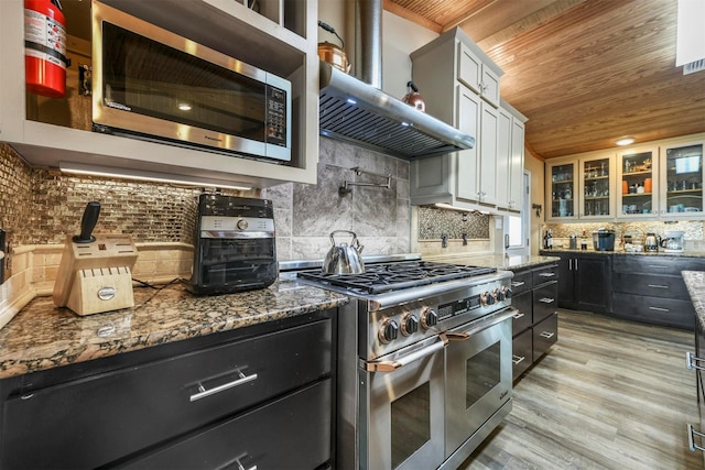 kitchen featuring white cabinetry, decorative backsplash, wall chimney range hood, wood ceiling, and appliances with stainless steel finishes