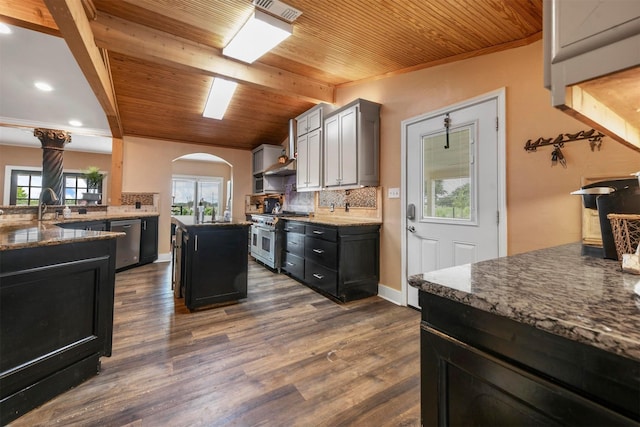 kitchen featuring wooden ceiling, tasteful backsplash, a kitchen island, dark hardwood / wood-style flooring, and appliances with stainless steel finishes