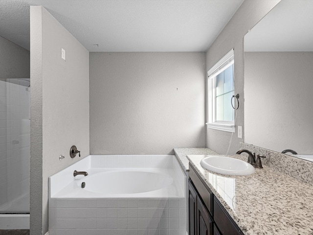 bathroom with independent shower and bath, a textured ceiling, and vanity