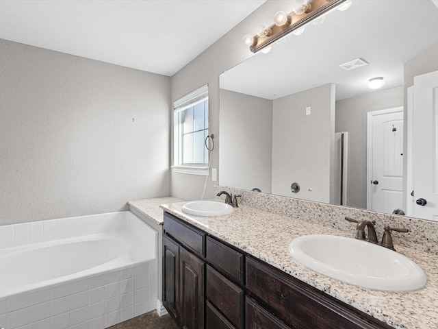 bathroom featuring vanity and tiled bath