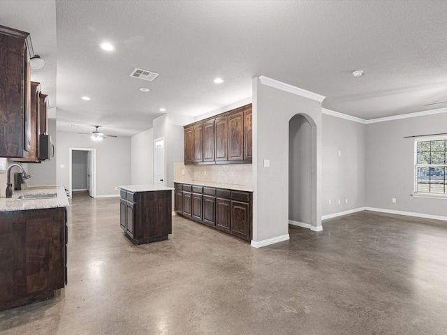 kitchen with sink, a textured ceiling, backsplash, dark brown cabinets, and a kitchen island