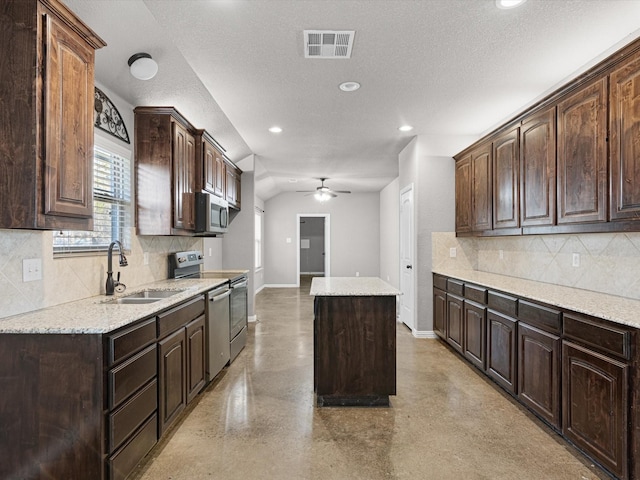 kitchen with appliances with stainless steel finishes, ceiling fan, a kitchen island, sink, and dark brown cabinets