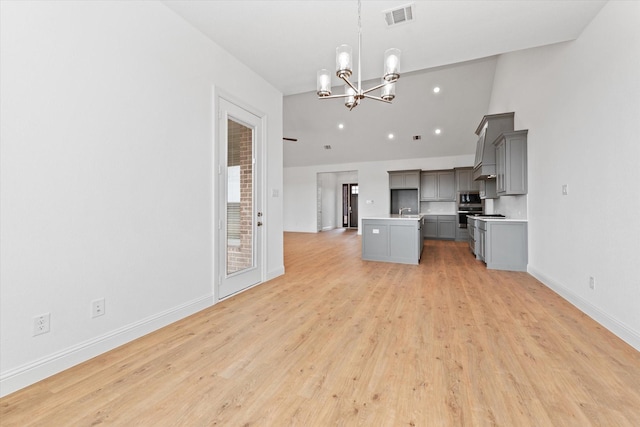 kitchen with gray cabinets, hanging light fixtures, a kitchen island, light hardwood / wood-style flooring, and an inviting chandelier