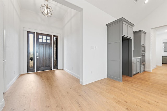 entryway featuring vaulted ceiling, light wood-type flooring, and a notable chandelier