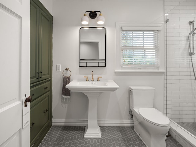 bathroom with toilet, a tile shower, and tile patterned floors