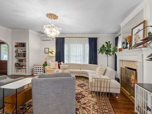 living room with a tile fireplace, an AC wall unit, ornamental molding, dark hardwood / wood-style flooring, and an inviting chandelier