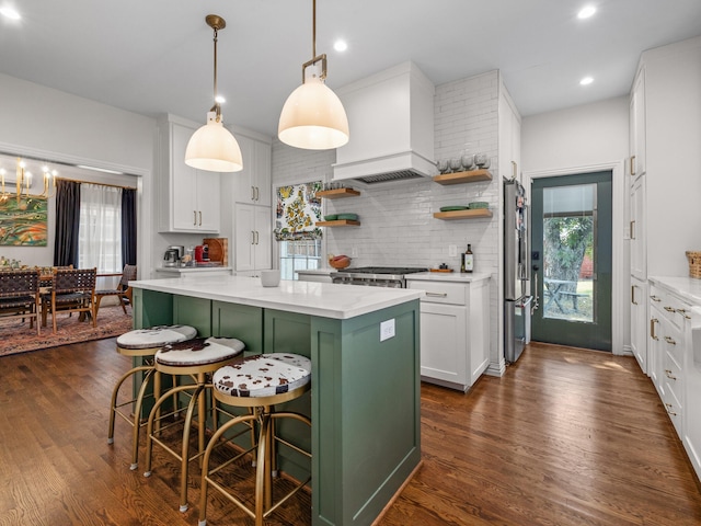 kitchen with white cabinets, a center island, a kitchen breakfast bar, hanging light fixtures, and premium range hood