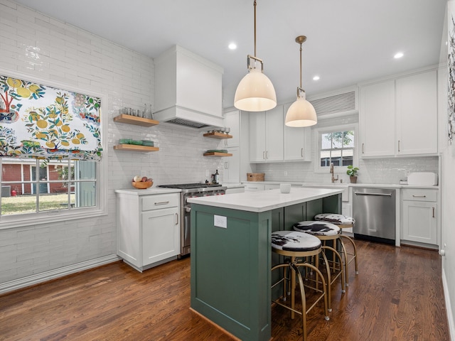 kitchen with a kitchen island, a kitchen bar, appliances with stainless steel finishes, and white cabinetry