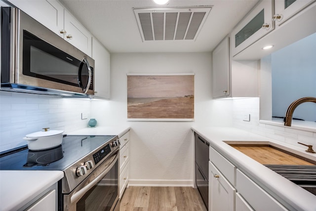 kitchen with tasteful backsplash, stainless steel appliances, and white cabinetry