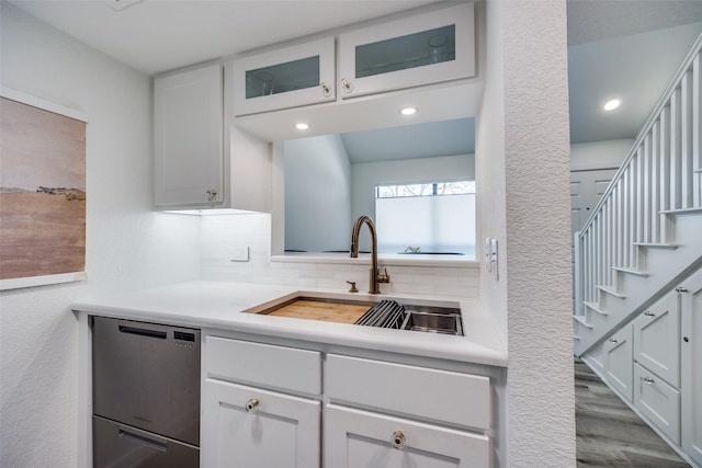 kitchen featuring hardwood / wood-style floors, tasteful backsplash, dishwasher, white cabinets, and sink