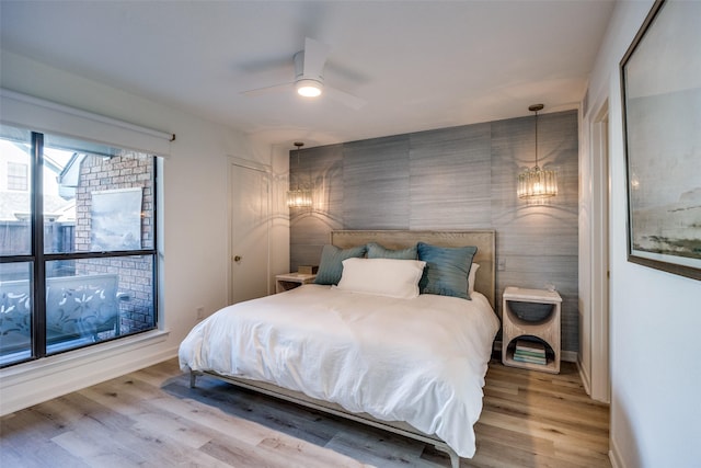 bedroom featuring wood-type flooring and ceiling fan with notable chandelier