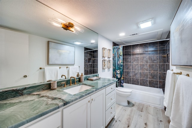 full bathroom with a textured ceiling, hardwood / wood-style floors, vanity, toilet, and shower / bath combo with shower curtain