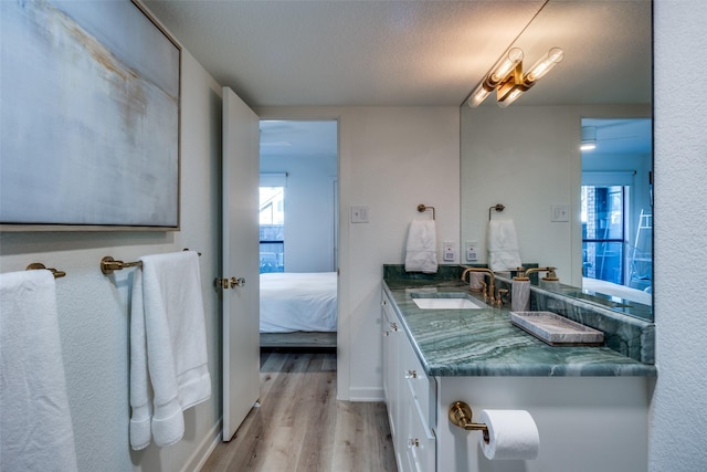 bathroom featuring a textured ceiling, a healthy amount of sunlight, hardwood / wood-style flooring, and vanity