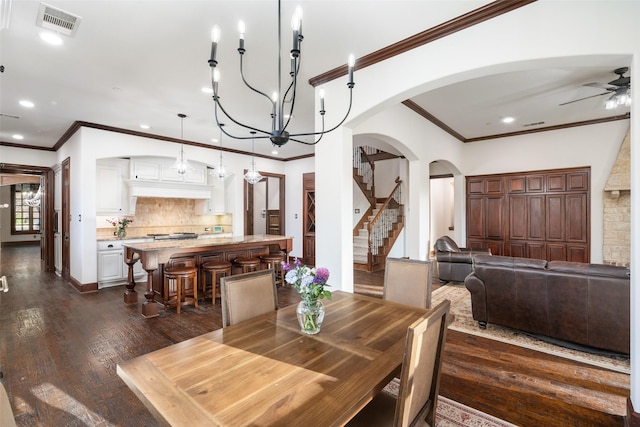 dining space with ceiling fan with notable chandelier, ornamental molding, and dark hardwood / wood-style floors