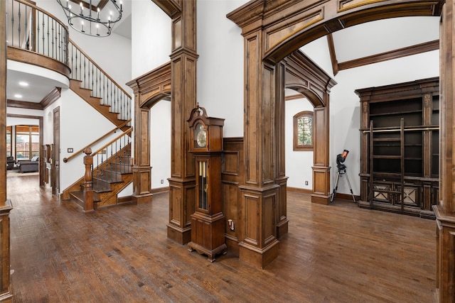 interior space with plenty of natural light, a towering ceiling, wood-type flooring, and ornate columns