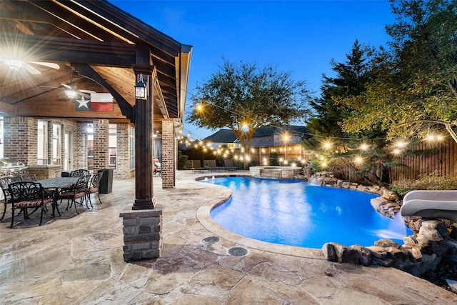 pool at dusk with a patio, ceiling fan, and an in ground hot tub