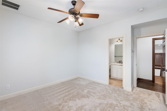 unfurnished bedroom featuring sink, ensuite bathroom, ceiling fan, and light colored carpet