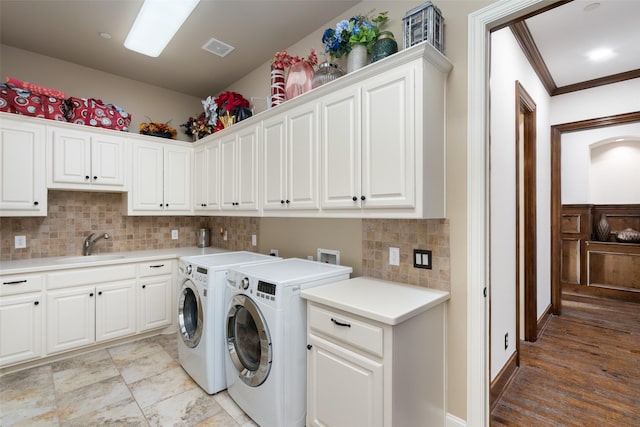 clothes washing area featuring sink, cabinets, crown molding, and washer and dryer