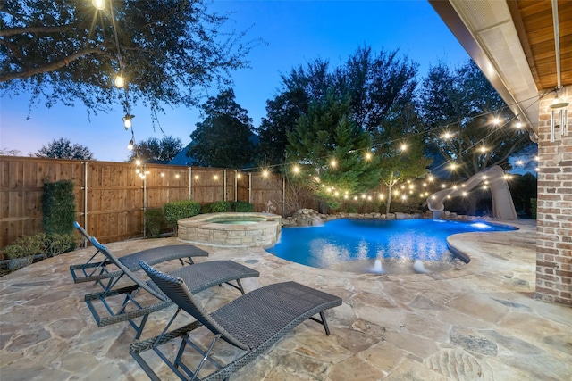 pool at dusk featuring an in ground hot tub and a patio