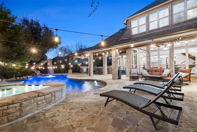 pool at dusk featuring an outdoor hangout area, a bar, a patio area, and pool water feature