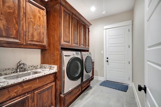 clothes washing area featuring sink, cabinets, washer and clothes dryer, and light tile patterned floors