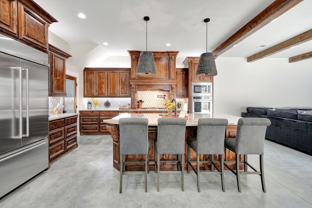 kitchen featuring hanging light fixtures, built in appliances, a kitchen bar, a kitchen island, and backsplash