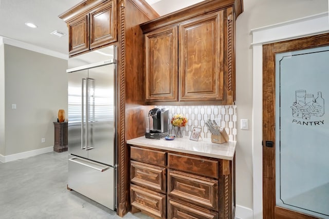 kitchen with stainless steel built in refrigerator, decorative backsplash, and crown molding