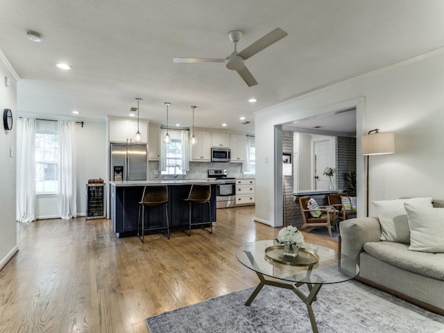 living room with sink, ceiling fan, crown molding, and light hardwood / wood-style flooring