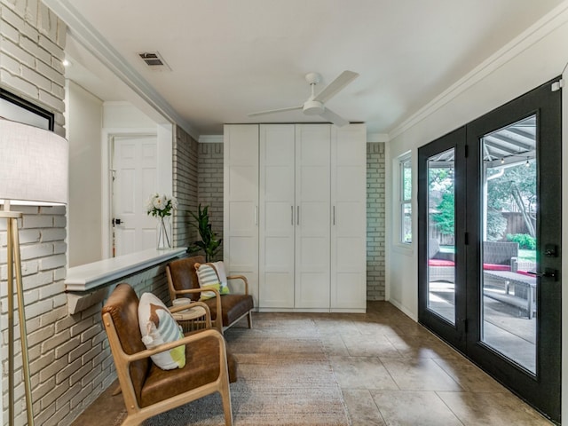 living area featuring ornamental molding, ceiling fan, and brick wall