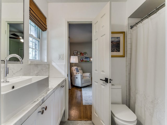 bathroom with toilet, ceiling fan, vanity, and decorative backsplash