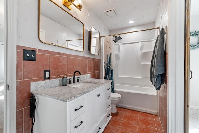 full bathroom with shower / tub combo, tile patterned flooring, toilet, vanity, and tile walls