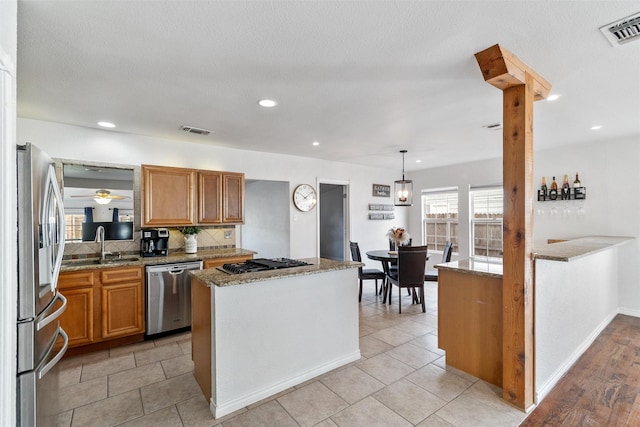 kitchen featuring stainless steel appliances, tasteful backsplash, hanging light fixtures, and kitchen peninsula