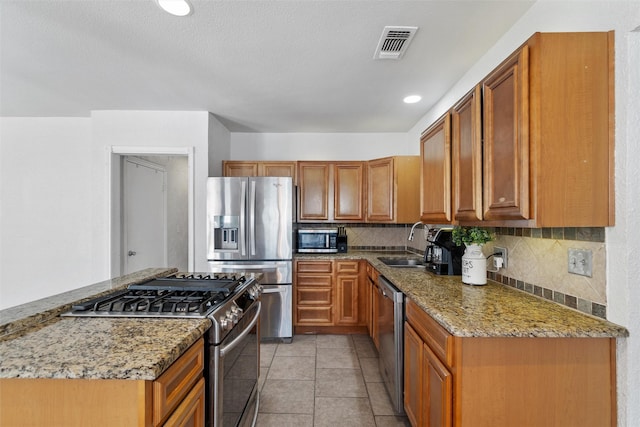 kitchen featuring stainless steel appliances, tasteful backsplash, light tile patterned floors, and light stone countertops