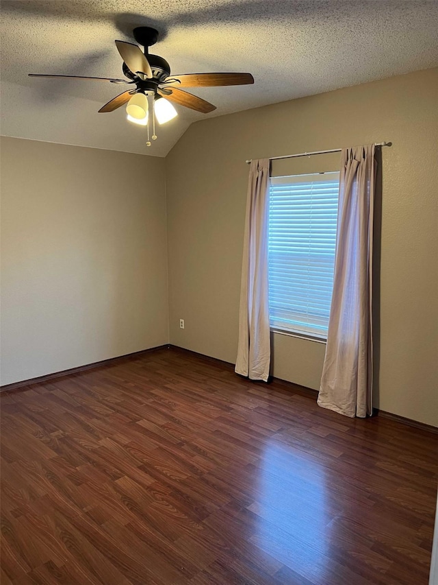 spare room featuring lofted ceiling, dark wood-type flooring, a textured ceiling, and ceiling fan