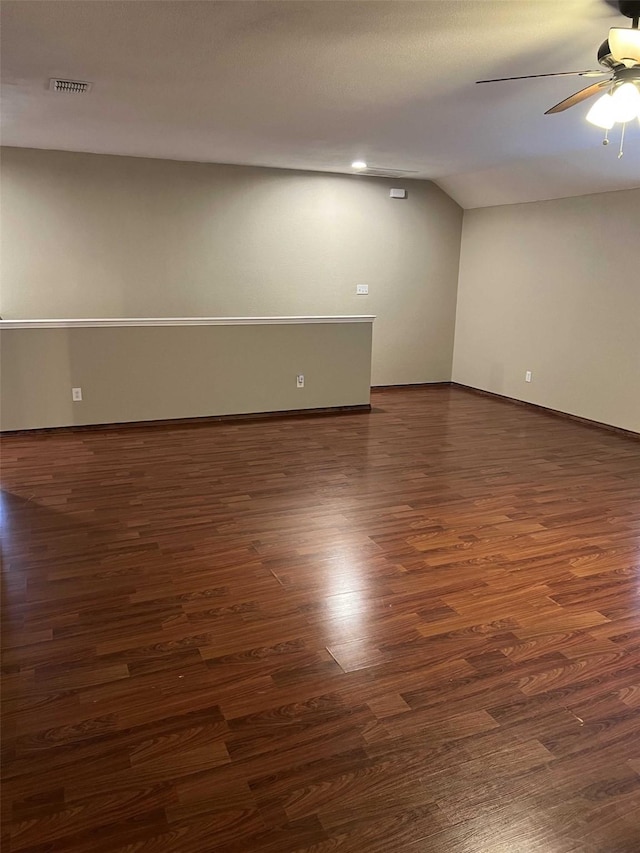 empty room featuring ceiling fan, vaulted ceiling, and dark hardwood / wood-style floors