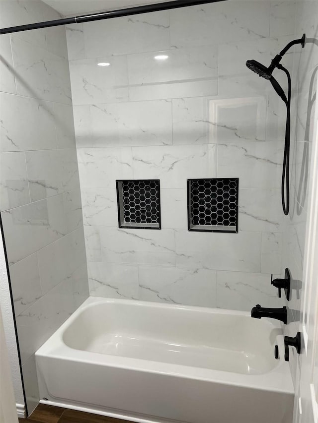 bathroom with hardwood / wood-style flooring and tiled shower / bath