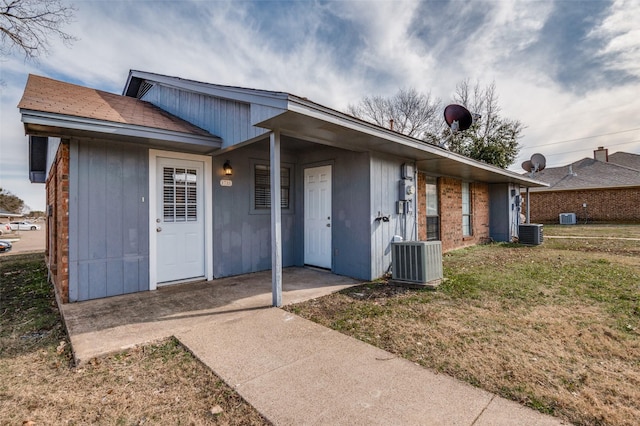 ranch-style house with a front yard and central AC unit