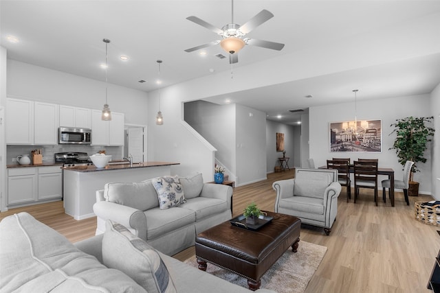 living room with sink, light hardwood / wood-style flooring, and ceiling fan with notable chandelier