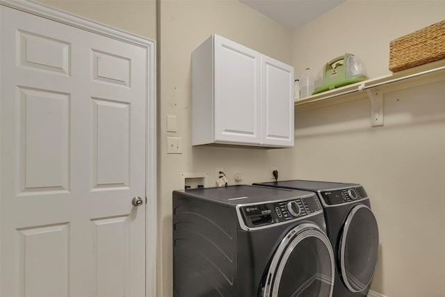 clothes washing area with cabinets and washing machine and dryer