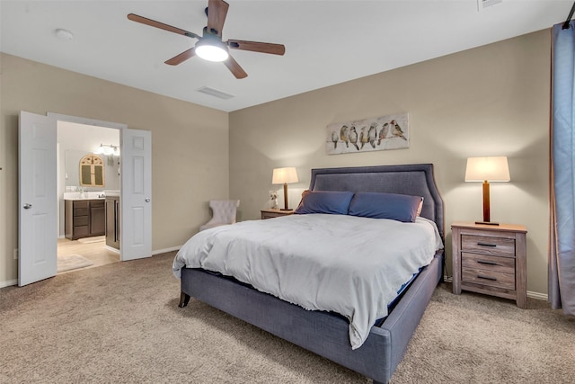 bedroom featuring ceiling fan, light colored carpet, and connected bathroom